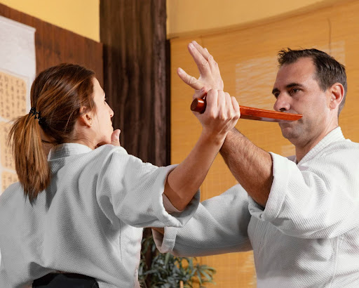 man-teachig-self-defense-techniques-to-a-woman-in-a-martial-arts-academy