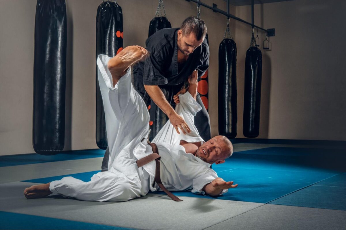 martial arts gym instructor evaluating student technique on clean mats